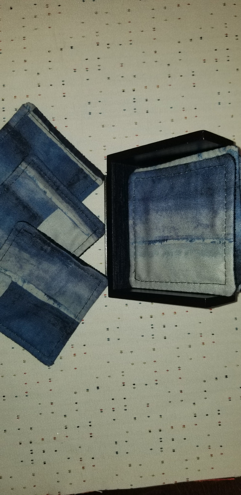 modern walnut pedestal coaster holder with classic blue, navy blue, and gray watercolor patterned coasters side view