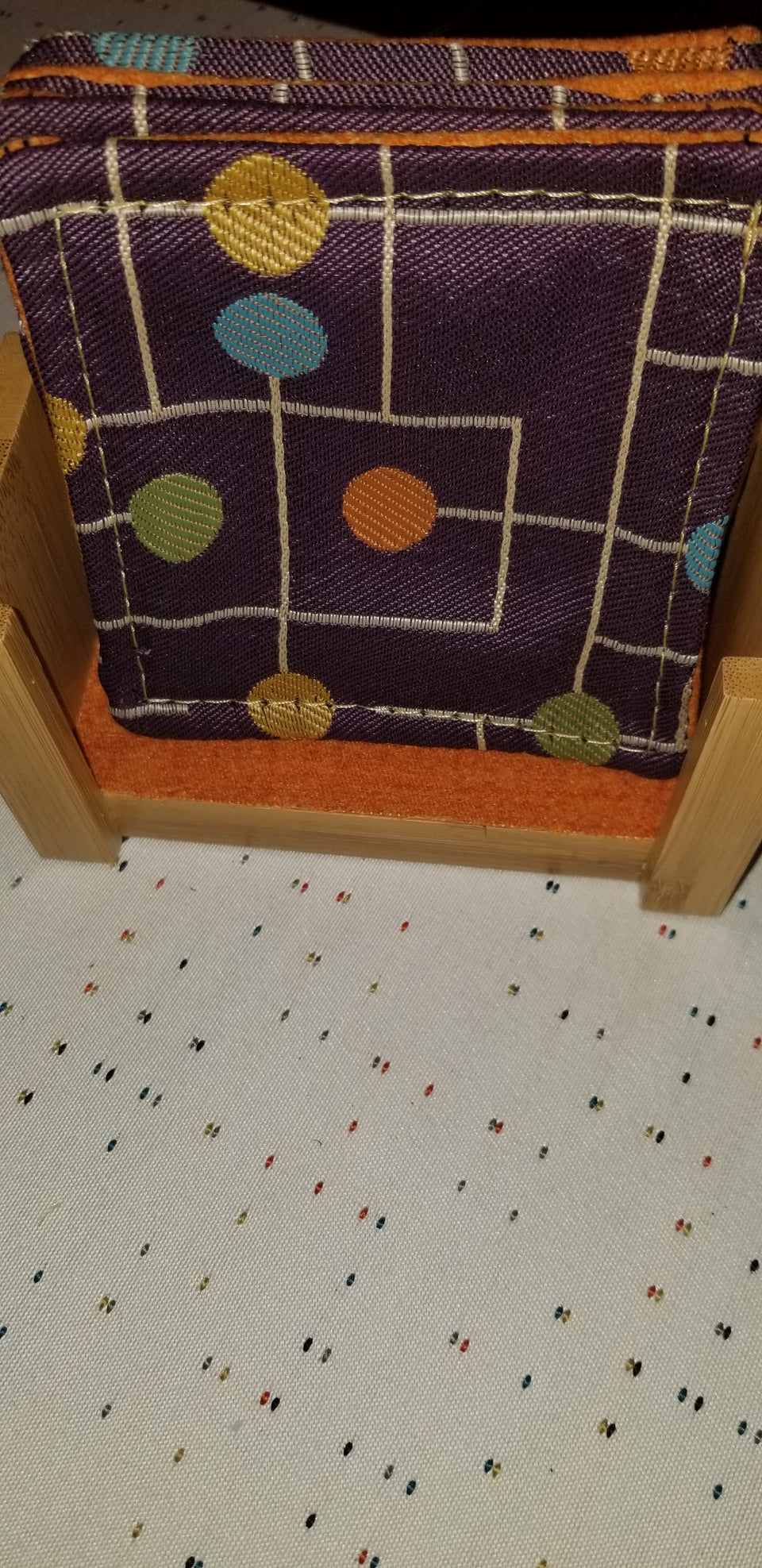 Bamboo coaster holder with purple and orange coasters, front view
