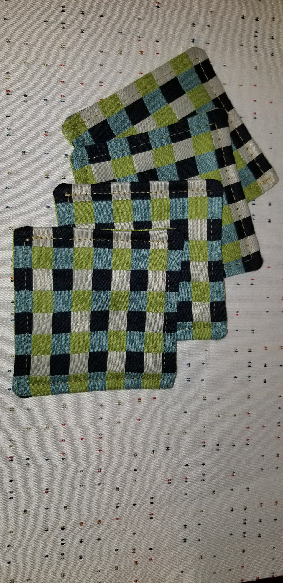 Set of (4) Chuck black, white, lime green, and turquoise gingham check patterned coasters top view.