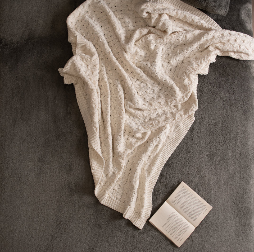 cable knitted beige throw cover in use on floor with book