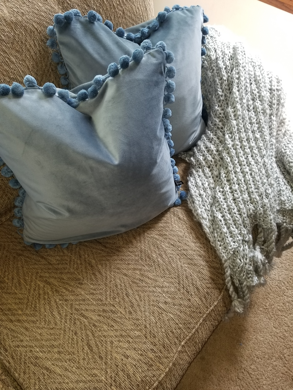 blue velour pillow covers with matching pom pom trim on khaki couch with gray throw cover