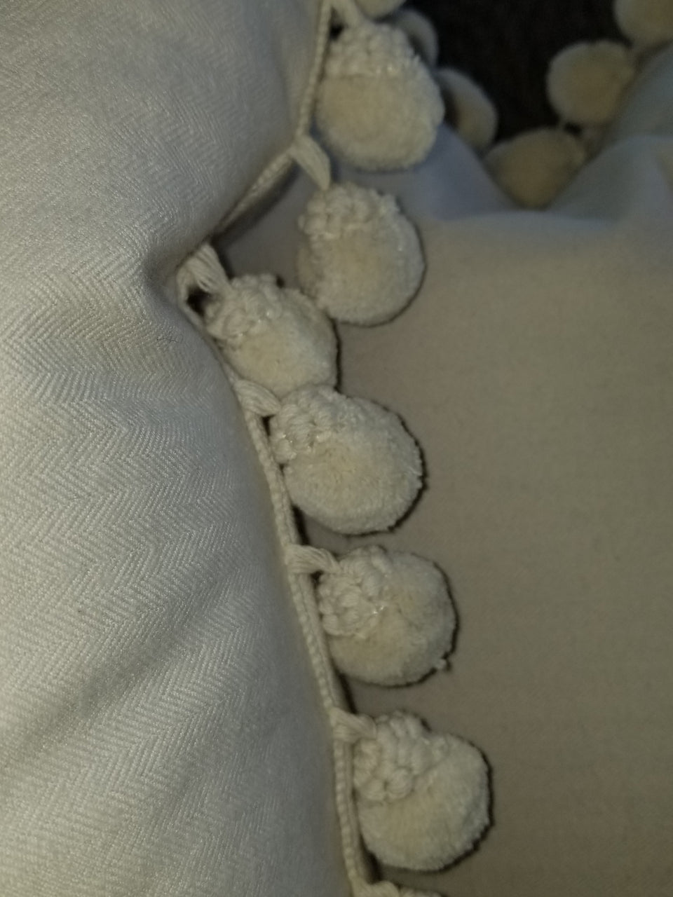 cream herringbone fleece fabric with gimp styled pom pom trim on a throw pillow cover