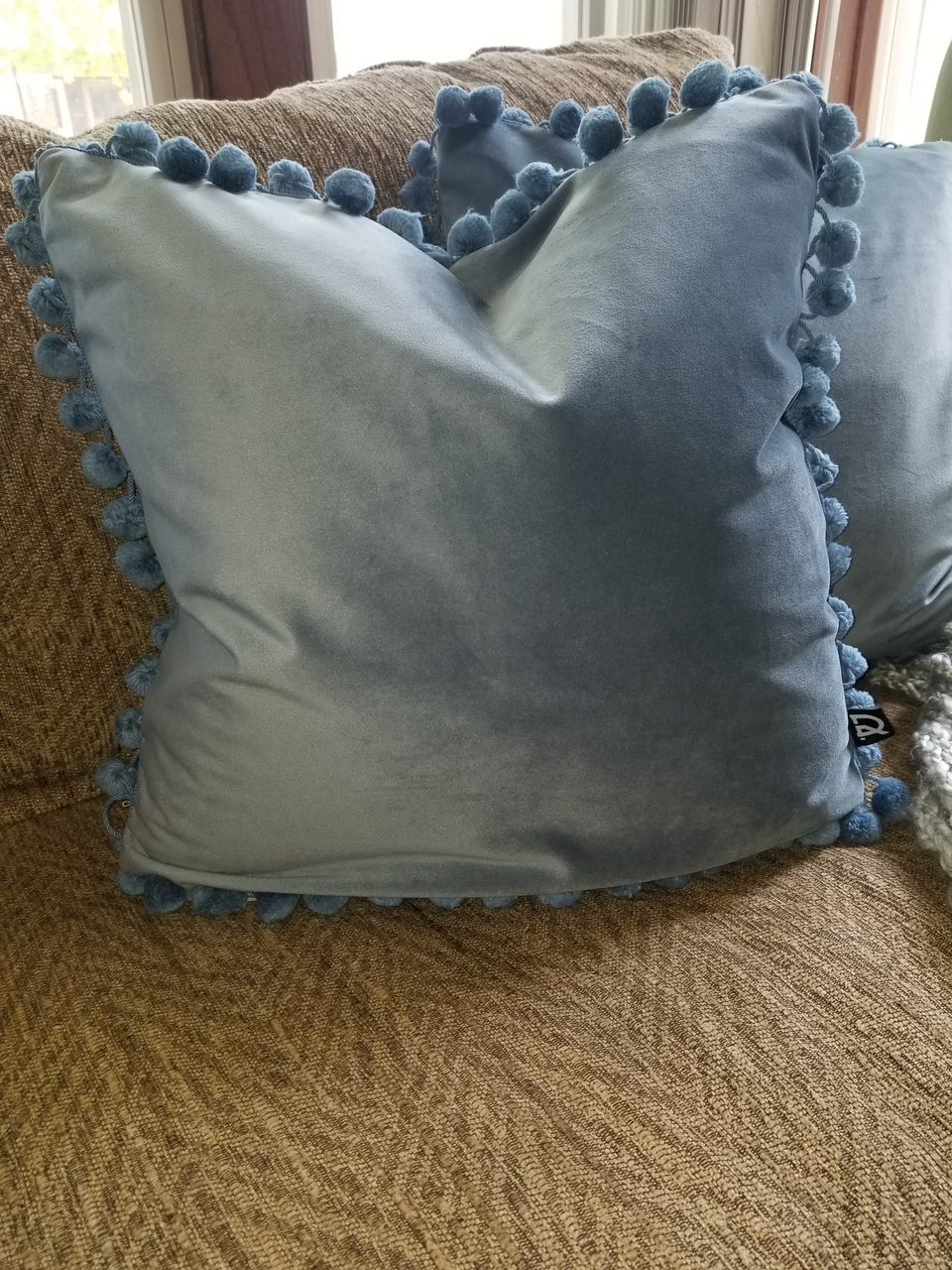 blue velour pillow covers with matching pom pom trim on khaki couch with gray throw cover