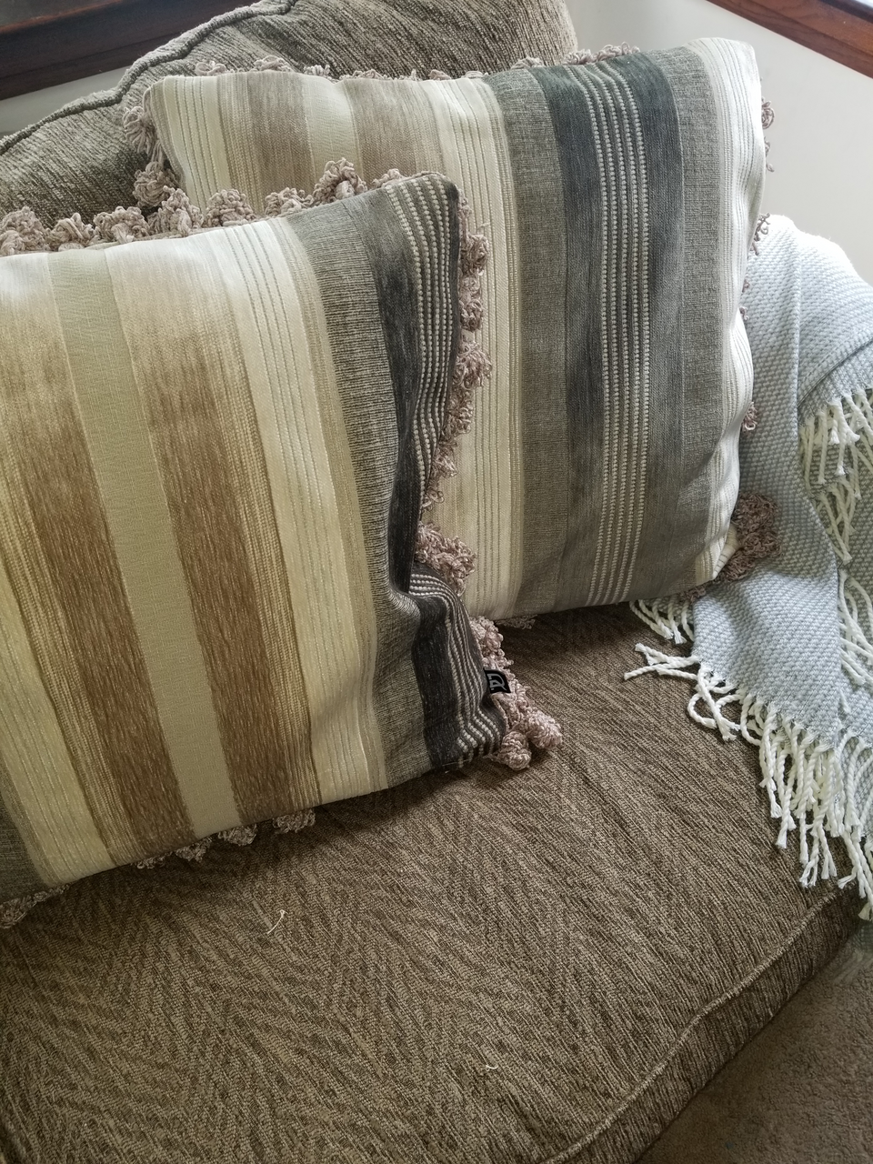 taupe and ivory velour stripe pillow cover with velour pom pom fringe trim on brown couch with taupe throw cover