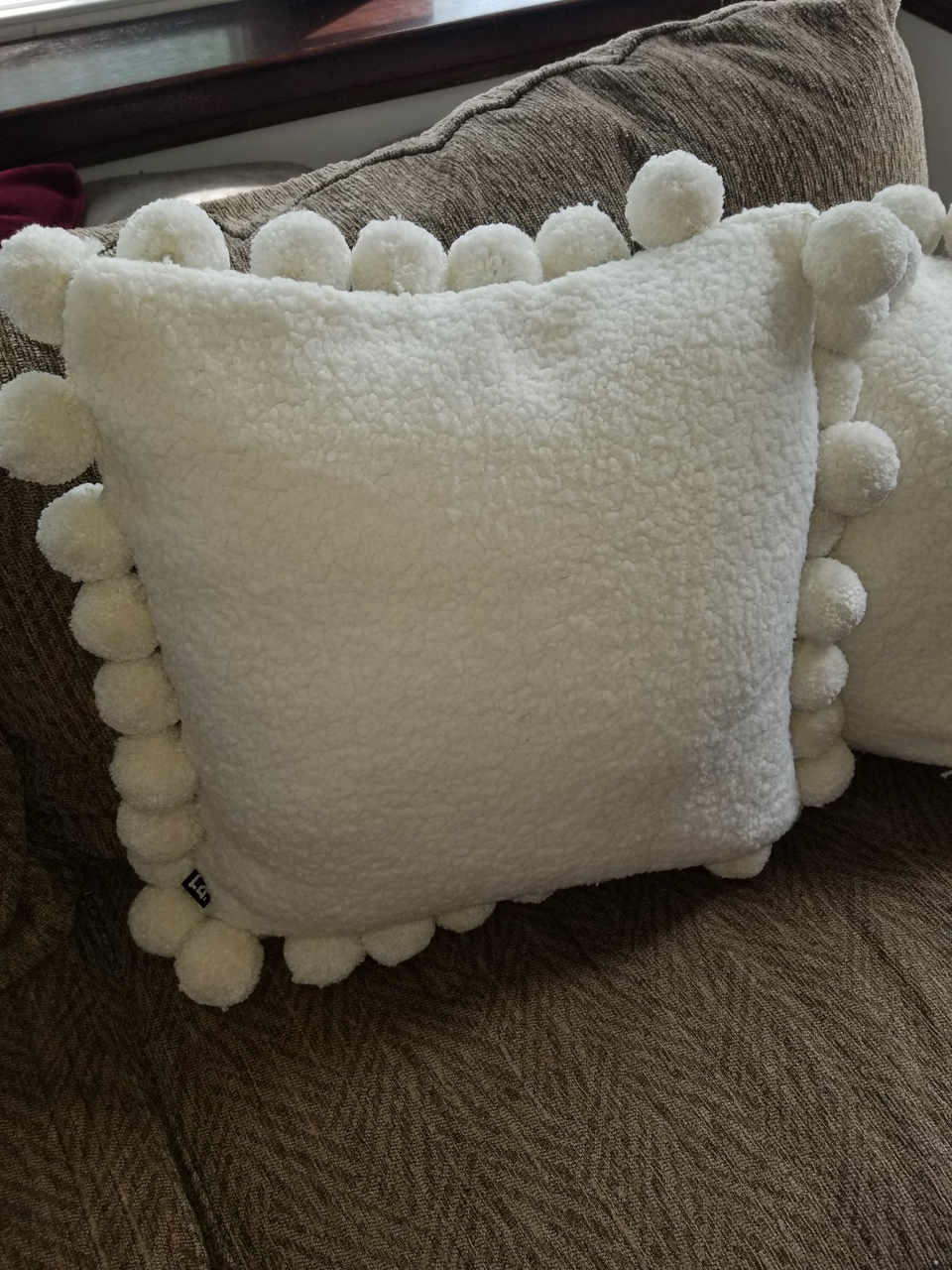 cream sherpa fleece jumbo pom pom pillow covers on a tan couch