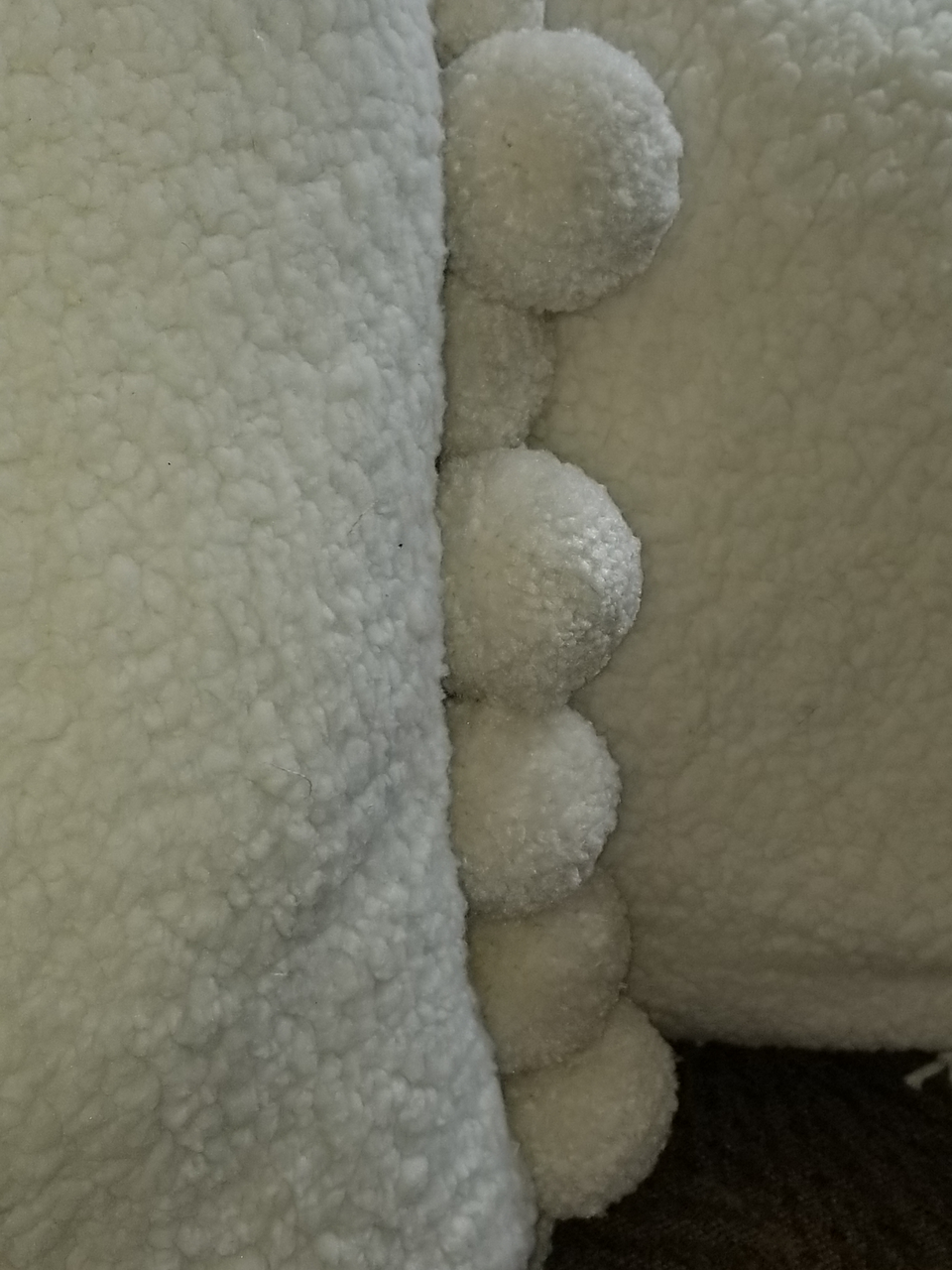 cream sherpa fleece jumbo pom pom pillow covers on a tan couch closeup trim detail