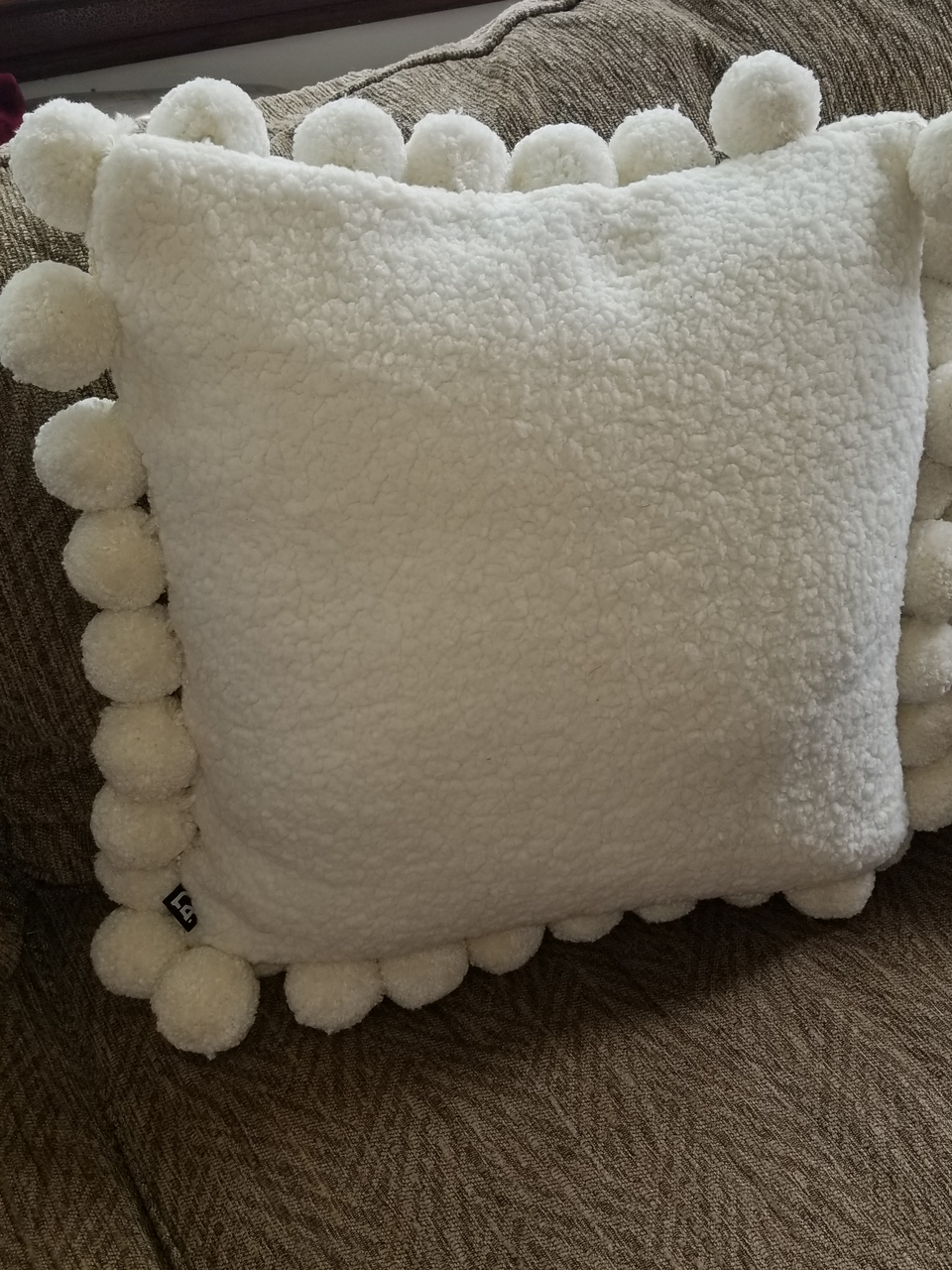 cream sherpa fleece jumbo pom pom pillow covers on a tan couch