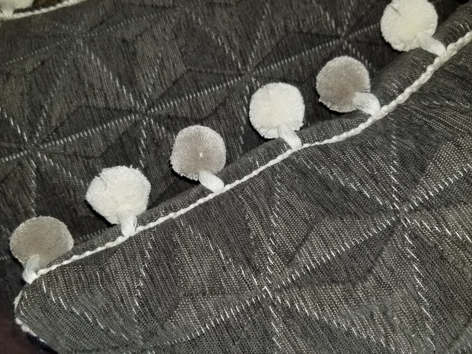 gray textured pillow covers with pom pom trim closeup detail