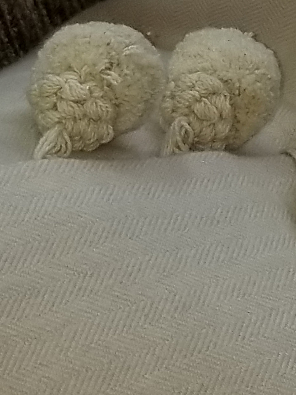 cream herringbone fleece fabric with gimp styled pom pom trim on a throw pillow cover
