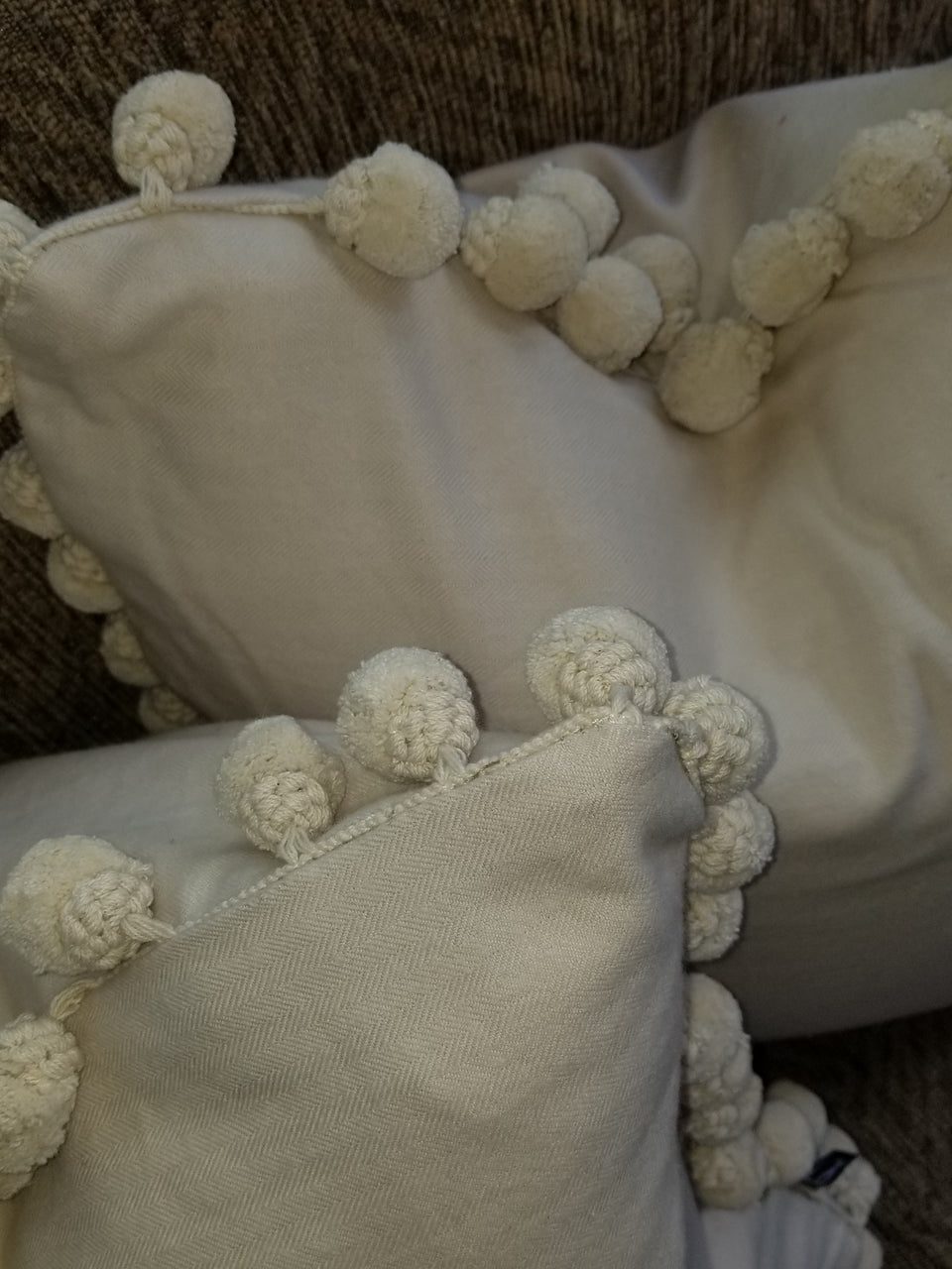 18 x 18 cream pom pom pillow covers on brown couch with beige throw cover top view detail