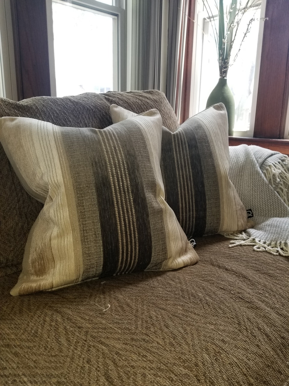 taupe and ivory velour stripe pillow covers on brown couch with taupe throw cover